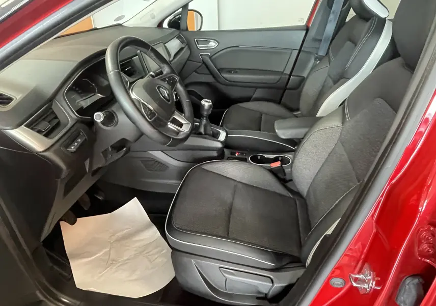 Vue intérieure côté conducteur du Renault Captur rouge 2019, montrant les sièges noirs et la boîte manuelle.