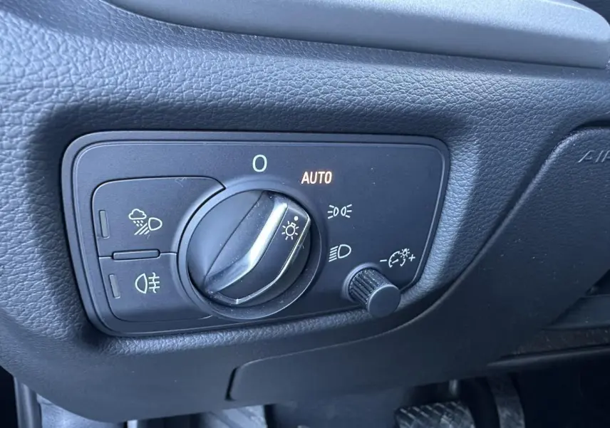Gros plan sur le bouton de commande des phares de l'Audi A3 2020, intérieur noir avec réglage automatique des feux.