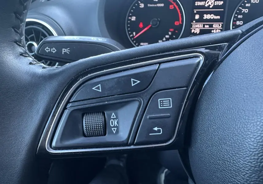 Gros plan sur les commandes multifonctions à gauche du volant cuir noir de l'Audi A3 berline 2020.