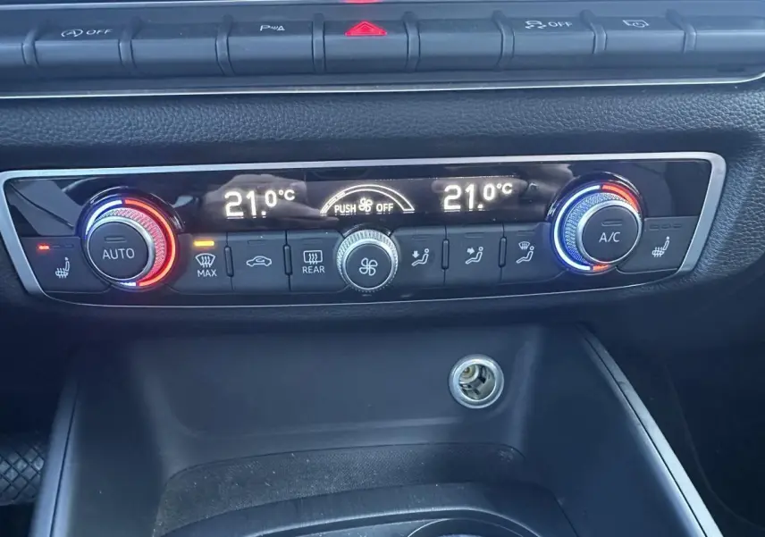 Vue rapprochée du tableau de bord de l'Audi A3 2020, montrant la climatisation automatique bi-zone avec réglages à 21°C.