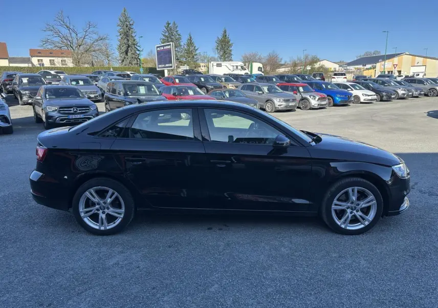 Audi A3 berline noire vue de profil côté gauche sur un parking en extérieur, jantes alliage 5 branches.