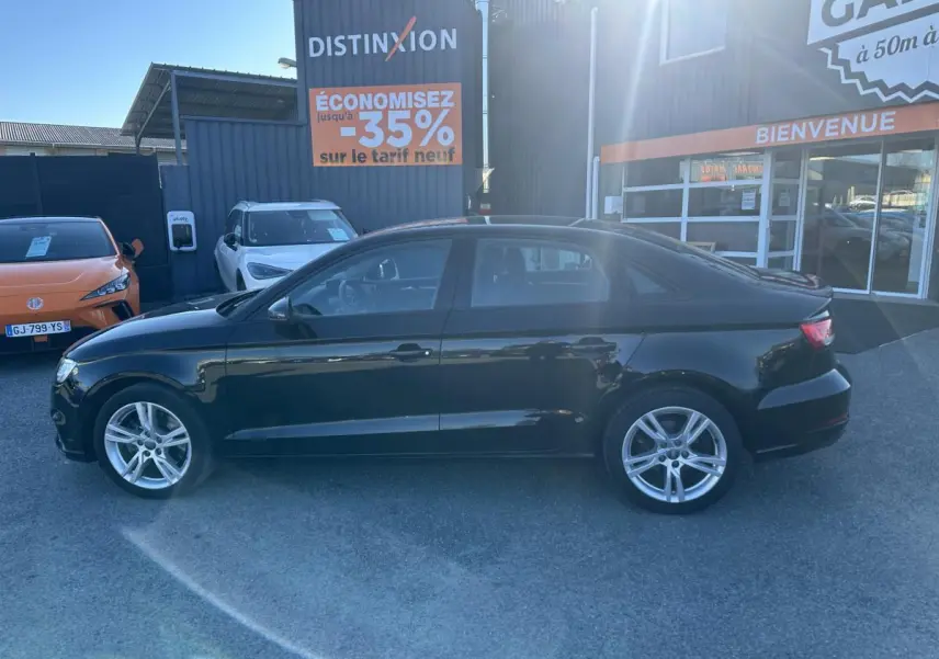 Audi A3 berline noire vue de profil côté gauche, avec jantes aluminium 10 branches et arrière compact.