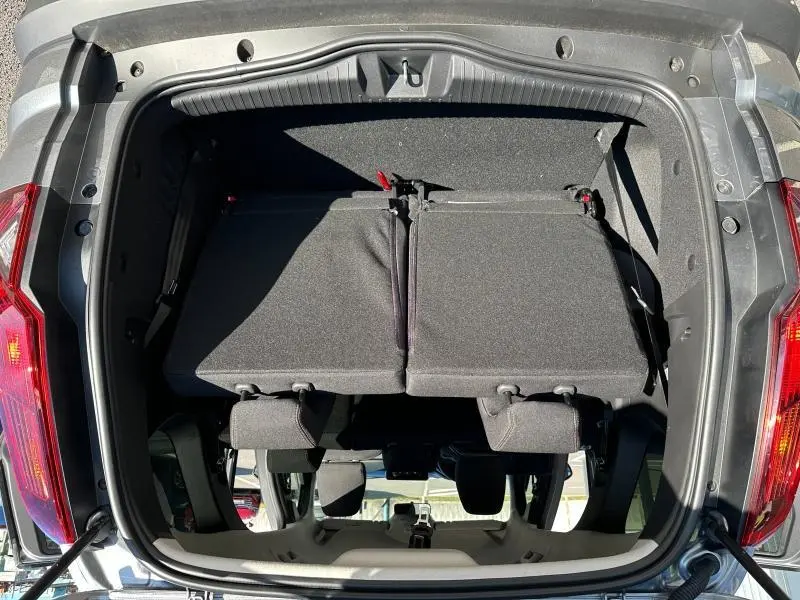 Vue plongeante sur le coffre ouvert du Dacia Jogger noir nacré, avec banquette arrière partiellement rabattue.