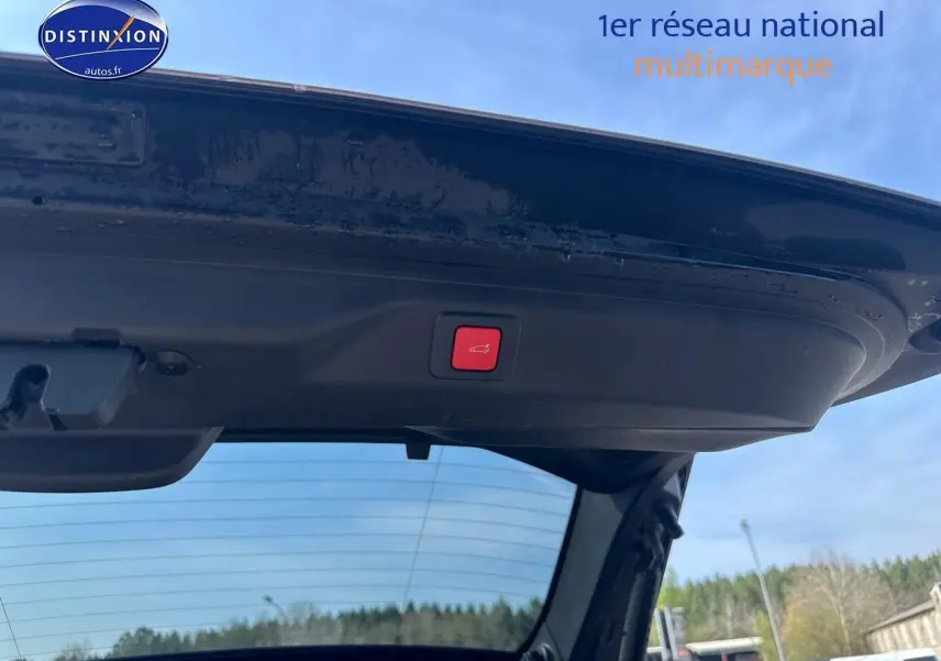 Vue depuis l'intérieur du coffre ouvert d'un Peugeot 3008 gris Artense, bouton rouge d'ouverture électrique visible sur le hayon.