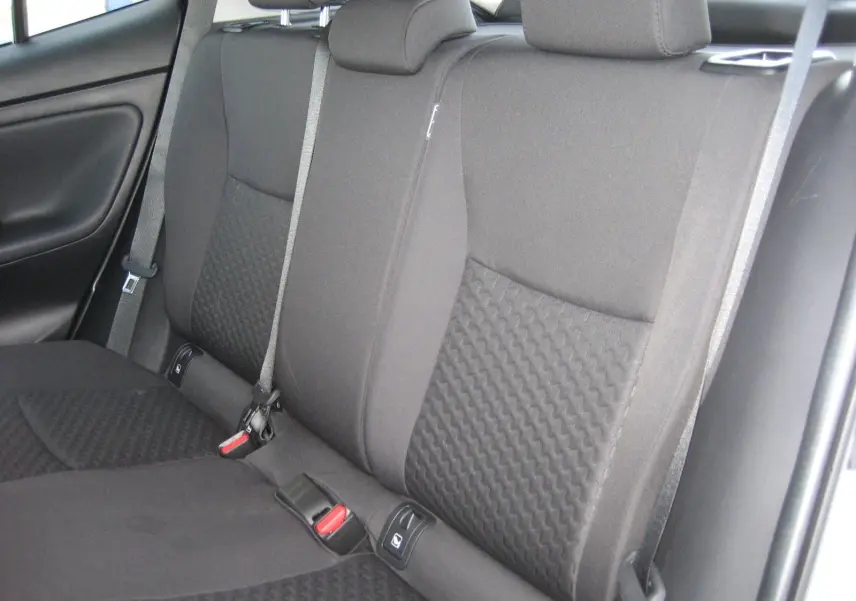 Vue intérieure des sièges arrière noirs en tissu texturé du Toyota Yaris Cross 2025, avec ceintures de sécurité visibles.