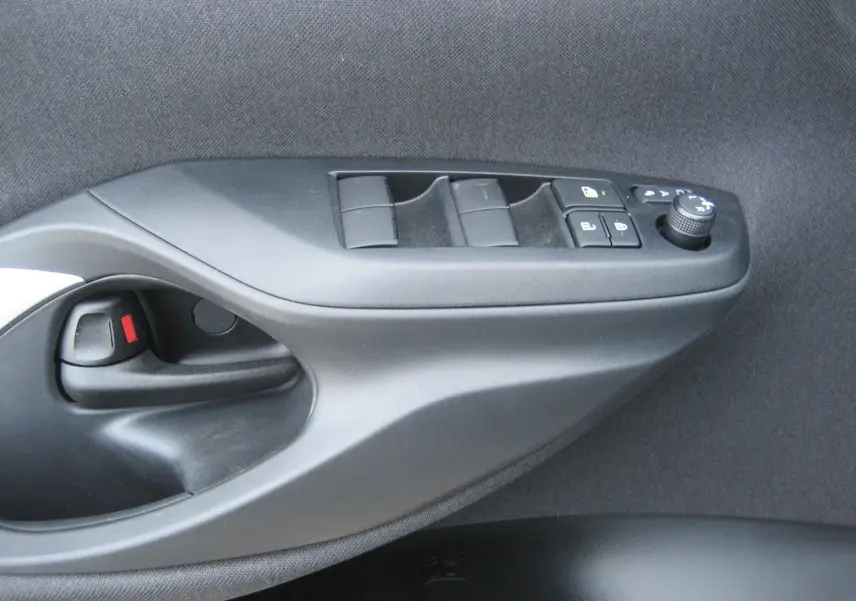 Gros plan sur la commande de porte côté gauche de la Toyota Yaris Cross 2025, avec boutons de réglage des vitres et rétroviseurs.