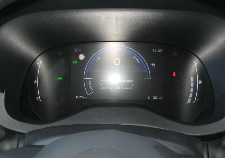 Vue rapprochée du tableau de bord numérique de la Toyota Yaris Cross blanc, affichant la consommation et l'autonomie.
