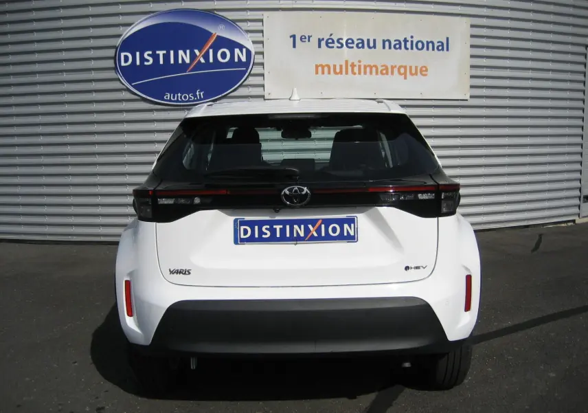 Vue arrière d'une Toyota Yaris Cross blanche 2025 avec feux arrière noirs et logo hybride visible.