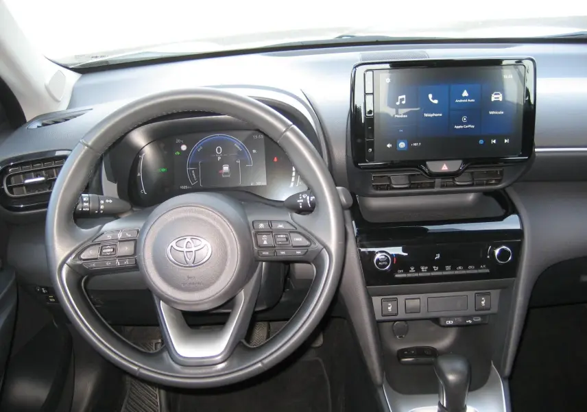 Vue intérieure du tableau de bord et volant noir de la Toyota Yaris Cross 2025, avec écran tactile central allumé.