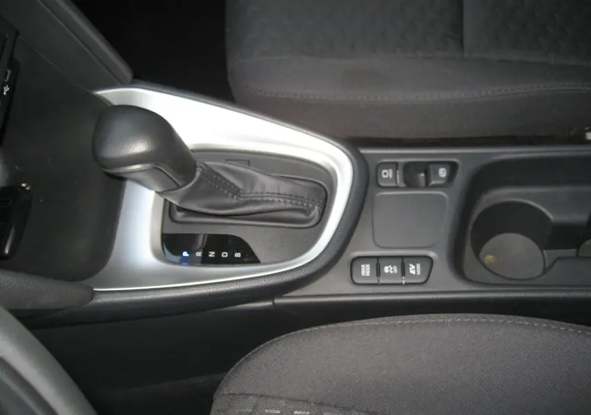 Gros plan sur la console centrale intérieure de la Toyota Yaris Cross 2025, avec levier de vitesse automatique et commandes hybrides.