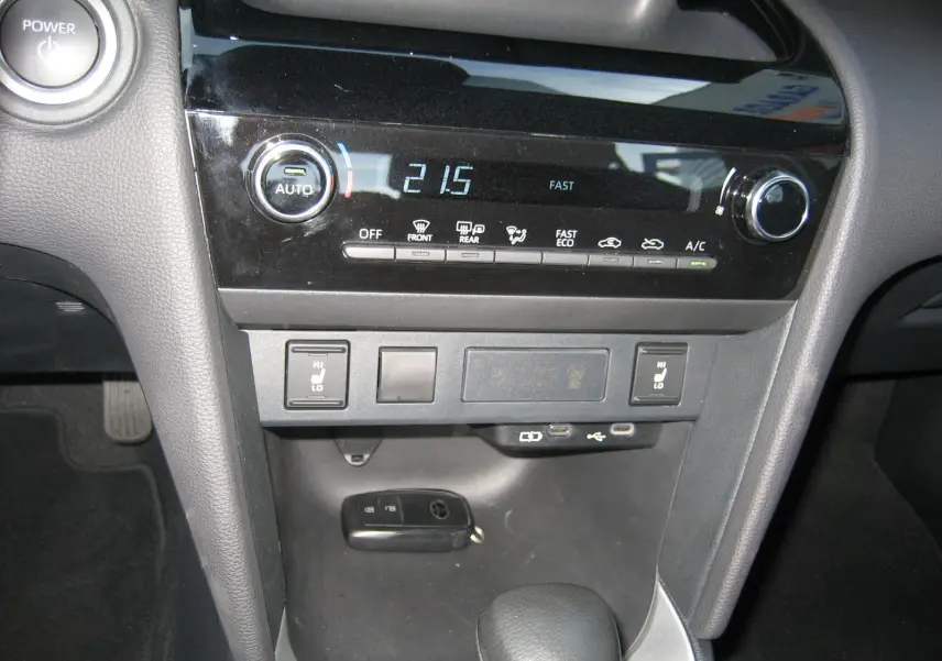 Vue rapprochée de la console centrale noire de la Toyota Yaris Cross blanche 2025, avec commandes climatisation et clé posée.