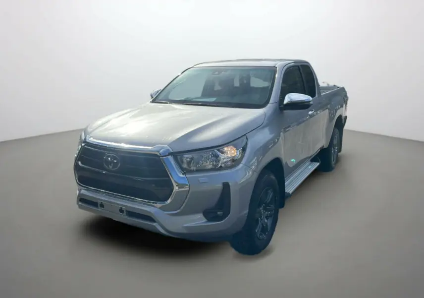Toyota Hilux 4x4 gris acier en 3/4 avant droit, avec calandre chromée et jantes foncées visibles.