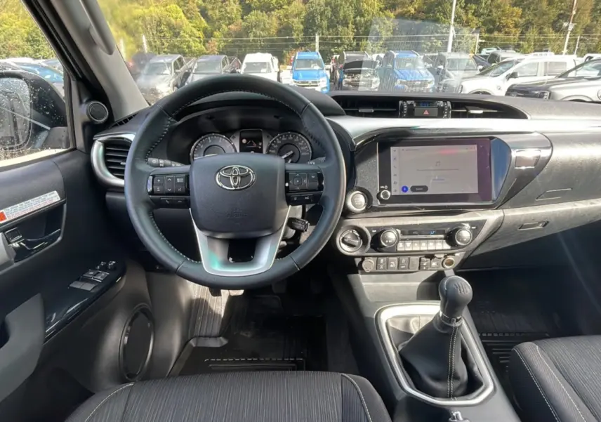 Intérieur du Toyota Hilux 2025 en vue frontale, montrant le volant, tableau de bord et levier de vitesse manuel.