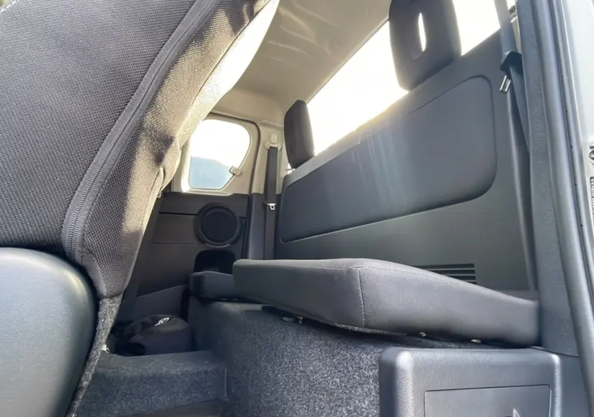 Vue intérieure arrière droite du Toyota Hilux 4x4 gris acier 2025, montrant la banquette rabattue et les finitions en tissu noir.