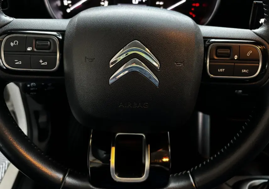 Gros plan sur le volant noir du Citroën C3 Aircross 2021 avec commandes intégrées et logo chromé central.