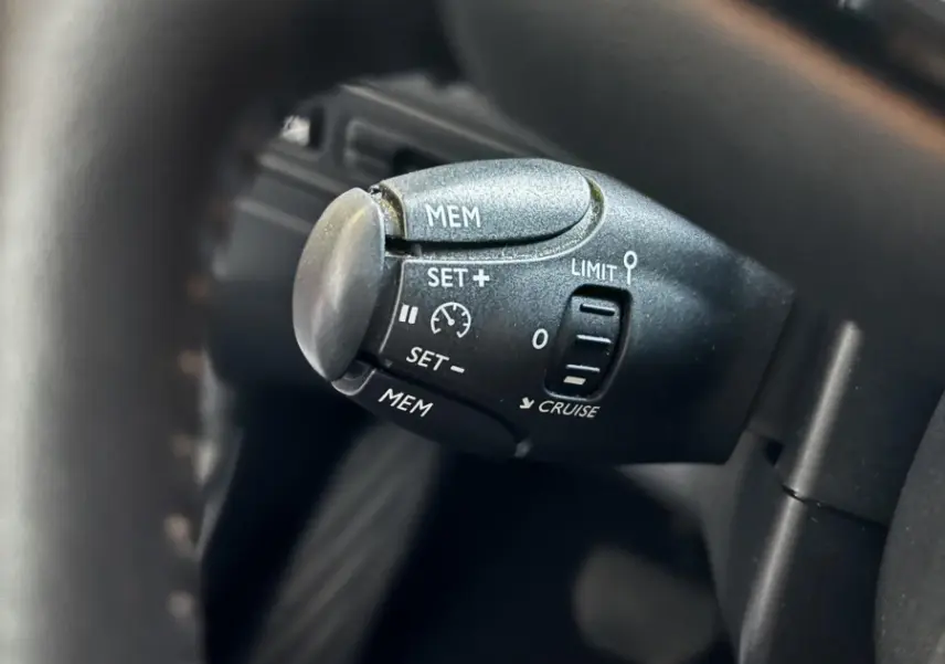 Gros plan sur la commande de régulateur de vitesse noire à gauche du volant d'un Citroën C3 Aircross blanc 2021.