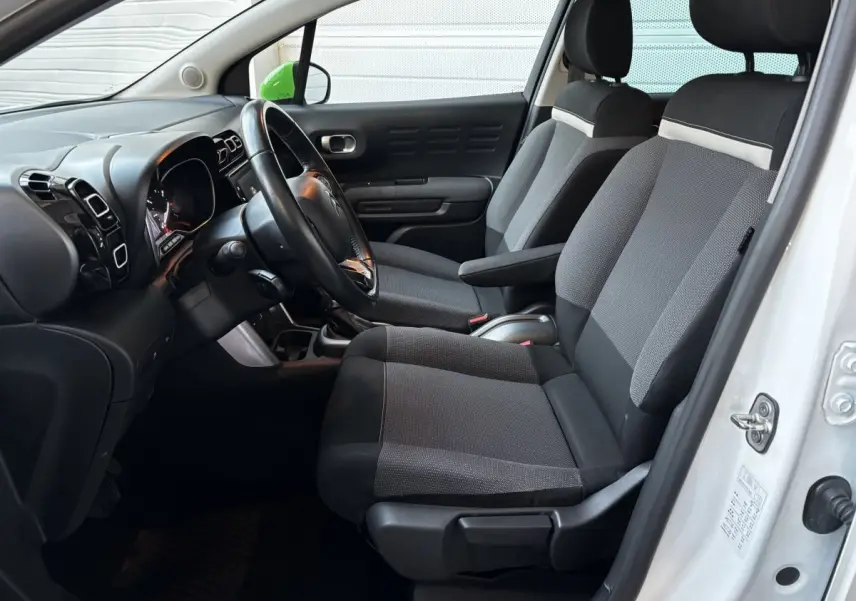 Intérieur avant droit d'une Citroën C3 Aircross blanc 2021 avec sièges gris et volant noir visible.