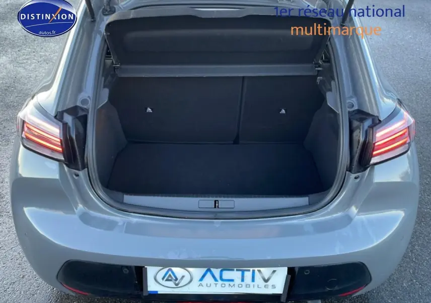 Vue arrière ouverte du coffre d'une Peugeot 208 1.2 100 Allure gris sélénite avec feux arrière allumés.