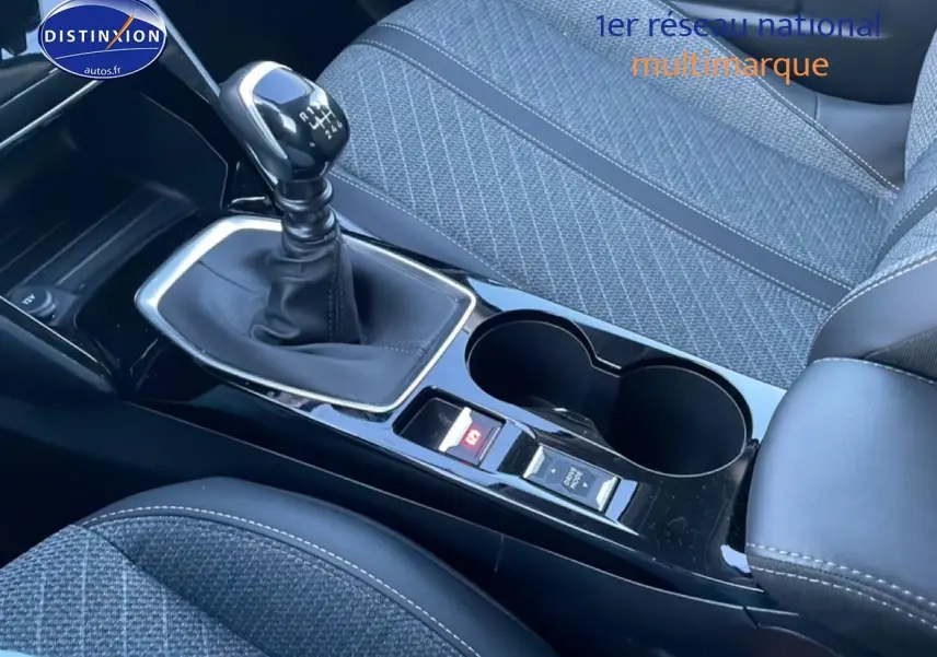 Gros plan sur la console centrale avec levier de vitesses manuel et sièges tissu gris de la Peugeot 208 1.2 100 Allure.