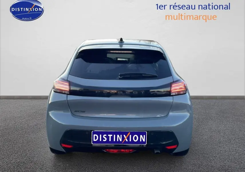 Vue arrière d'une Peugeot 208 1.2 100 allure gris sélénite avec feux arrière LED allumés sur fond neutre.