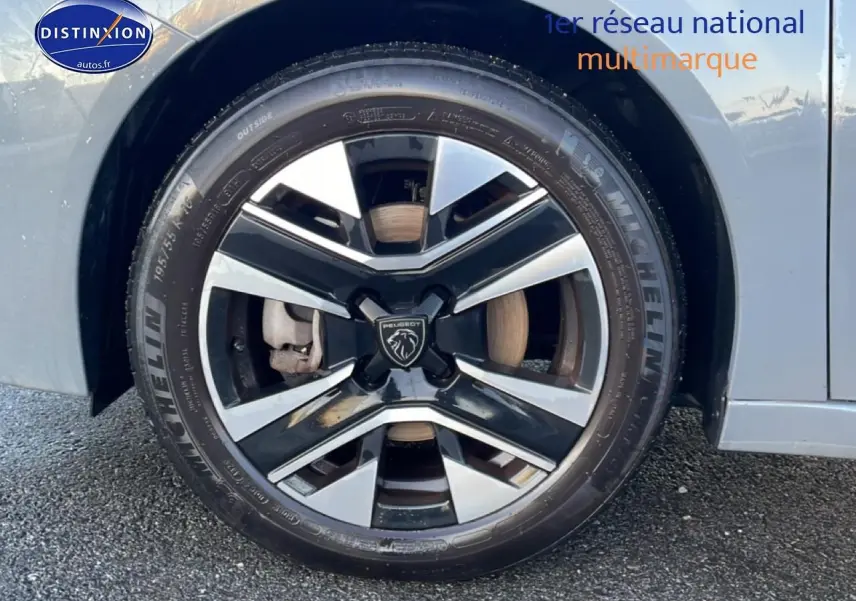 Gros plan sur la roue avant gauche de la Peugeot 208 gris sélénite avec jante alliage bicolore et pneu Michelin.