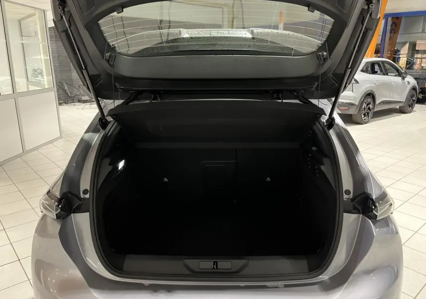 Coffre ouvert vu de l'arrière d'une Peugeot 308 Gris Artense dans un showroom lumineux.