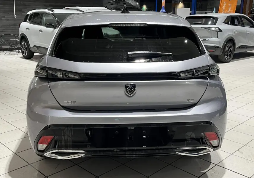Vue arrière d’une Peugeot 308 GT gris Artense avec feux arrière noirs brillants et double sortie d’échappement chromée.