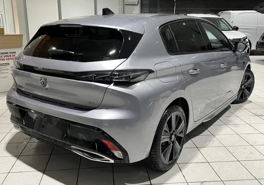 Vue 3/4 arrière droit d’une Peugeot 308 GT 2024 gris Artense avec feux arrière noirs brillants et jantes alliage 18 pouces.