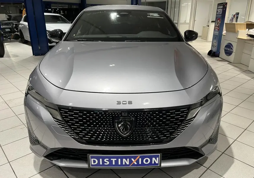 Vue avant frontale d'une Peugeot 308 gris Artense avec calandre noire brillante et logo lion central.