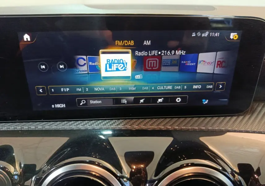 Écran tactile central de la Mercedes Classe A 250 e Business Line 2021 avec affichage radio FM/DAB, entouré de sorties d'air rondes chromées.