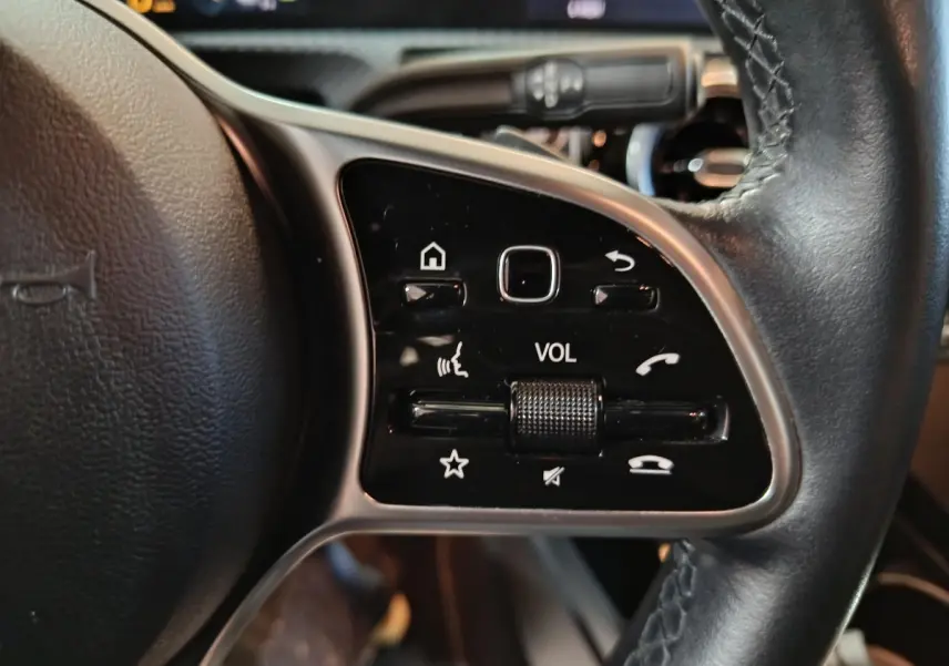 Gros plan sur le volant cuir côté gauche de la Mercedes Classe A 250 e Business Line bleu, avec commandes multifonctions.