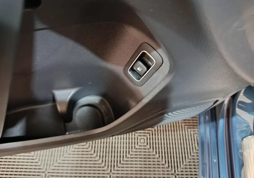 Détail intérieur du panneau de porte côté gauche avec bouton ouverture coffre, sur Mercedes Classe A bleu 2021.