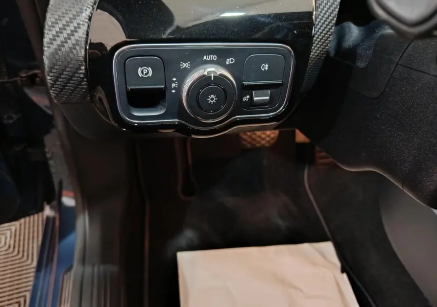 Gros plan sur les commandes d'éclairage et frein à main électrique dans une Mercedes Classe A 250 e Business Line bleu.