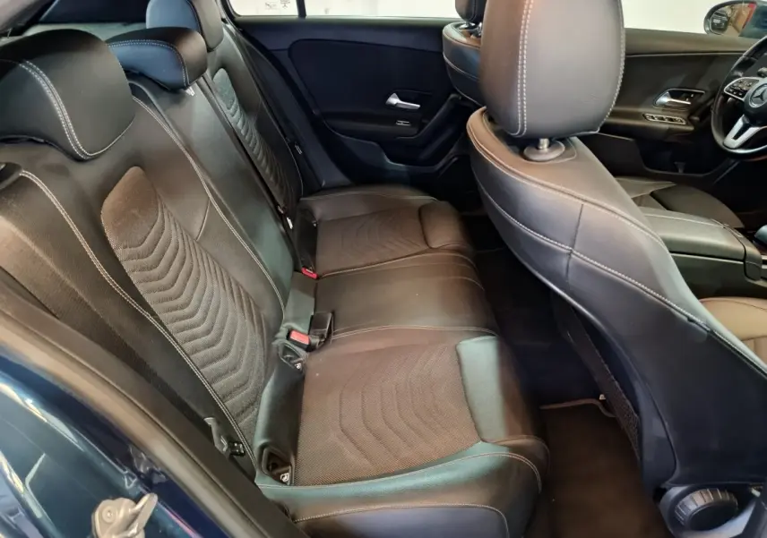 Vue intérieure côté arrière droit de la Mercedes Classe A 250 e Business Line 2021 avec sièges en cuir noirs et détails tissu.
