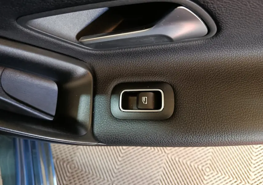 Bouton de commande de vitre électrique sur la porte intérieure côté gauche d’une Mercedes Classe A bleu.