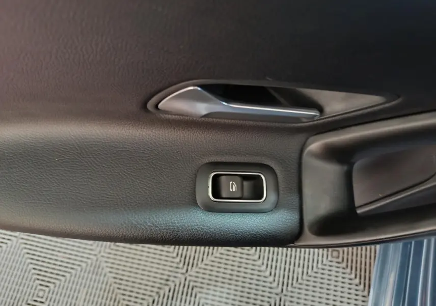 Gros plan sur la poignée intérieure et le bouton de verrouillage de la porte côté gauche d'une Mercedes Classe A bleu.