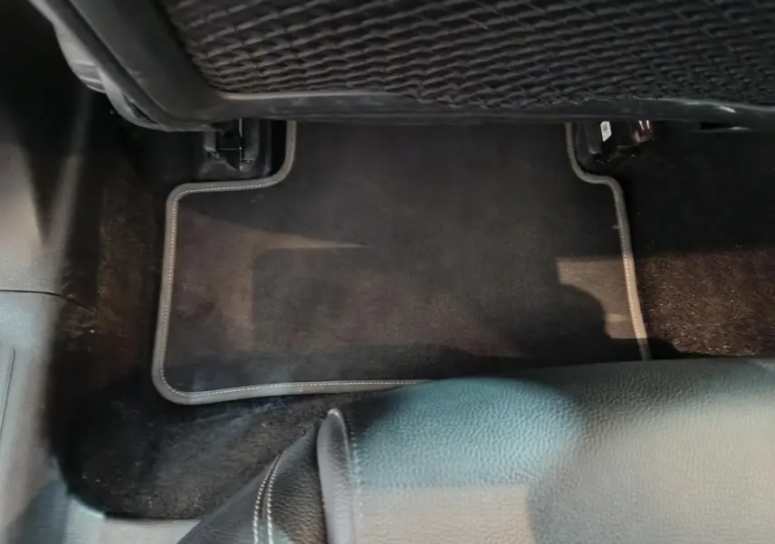 Vue rapprochée du tapis de sol noir et de la partie inférieure du siège en cuir dans une Mercedes Classe A bleu.