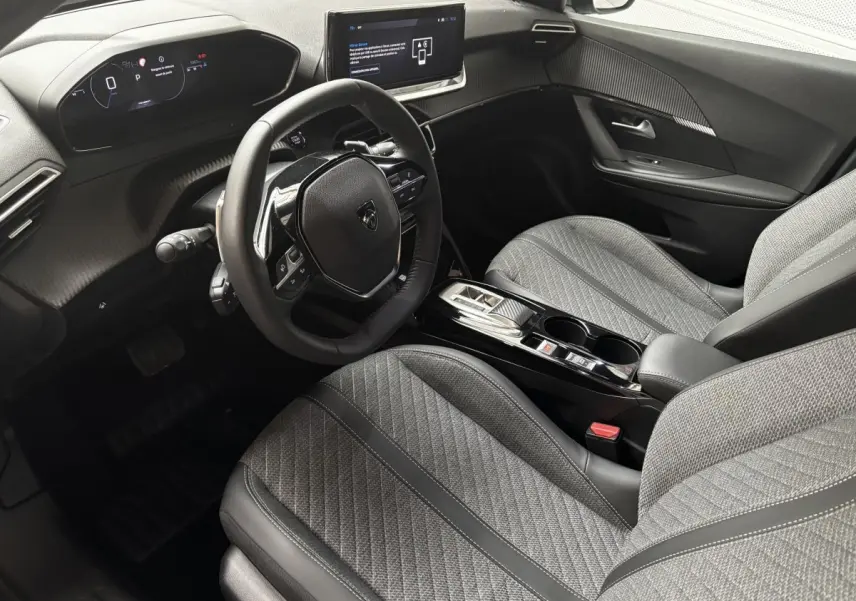 Vue intérieure côté conducteur du Peugeot 2008 Hybrid 145 e-DCS6 Allure 2025, sièges gris et tableau de bord digital.