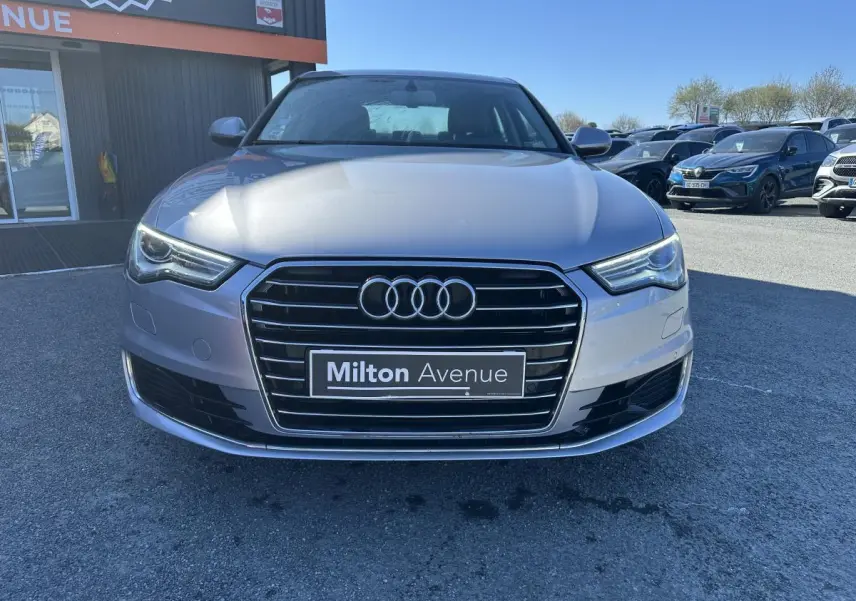 Vue avant d'une Audi A6 gris métallisé avec calandre Singleframe chromée et phares LED, stationnée en extérieur.