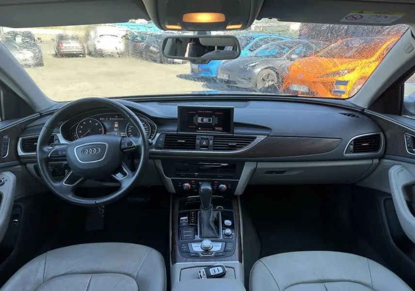 Vue intérieure avant de l'Audi A6 2015 avec tableau de bord et volant multifonction en cuir gris clair.