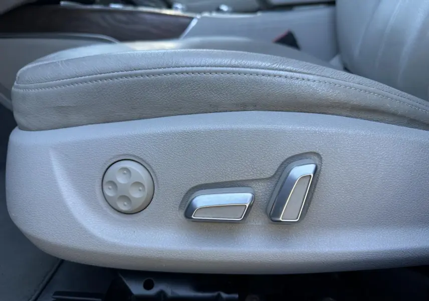 Gros plan sur les commandes de réglage électrique du siège avant en cuir gris clair de l'Audi A6 2.0 TFSI Ambiente.