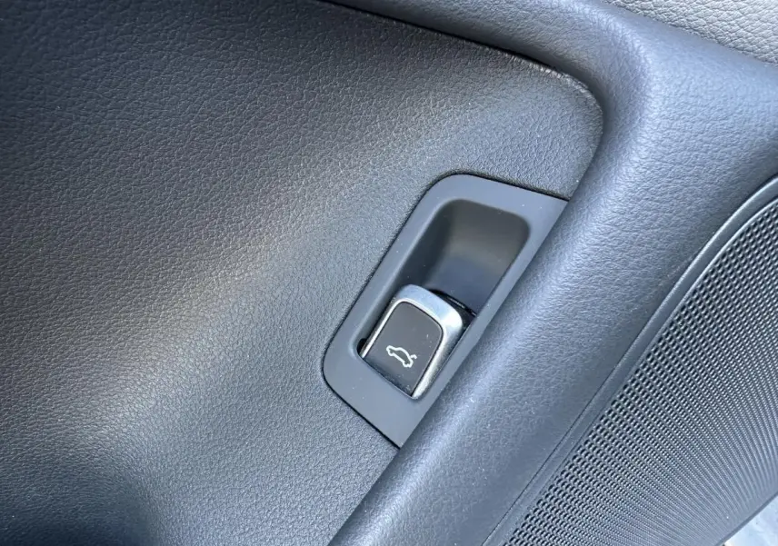 Bouton d'ouverture électrique du hayon sur la porte intérieure côté gauche d'une Audi A6 gris 2015.