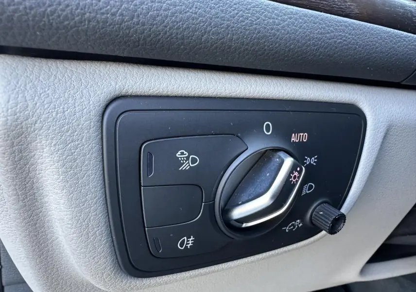 Gros plan sur la commande des phares de l’Audi A6 2015, avec molette en position automatique sur panneau gris clair.