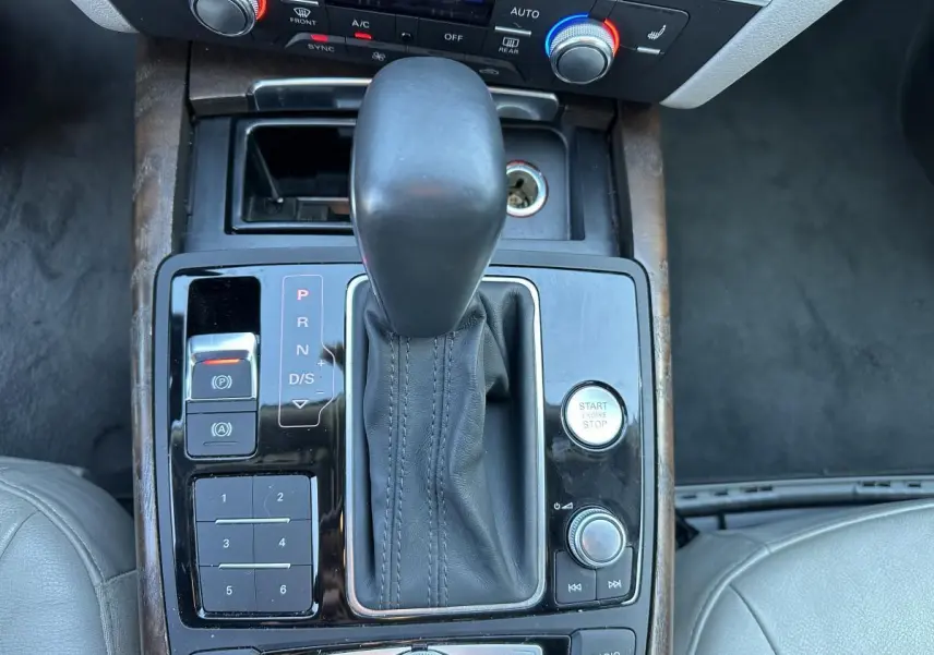 Vue rapprochée de la console centrale de l'Audi A6 2015, montrant levier de vitesses cuir et boutons de commande noirs.