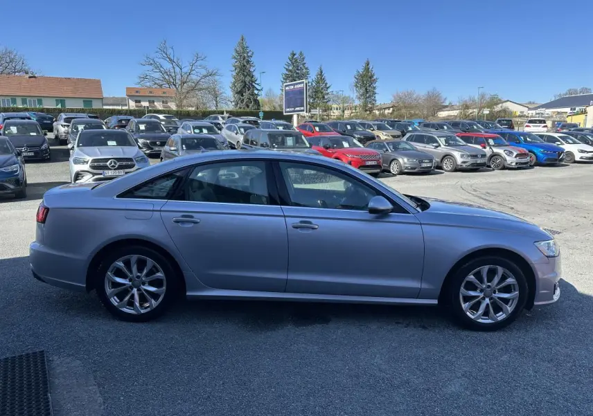 Audi A6 gris vue de profil côté gauche sur un parking en extérieur par temps clair.