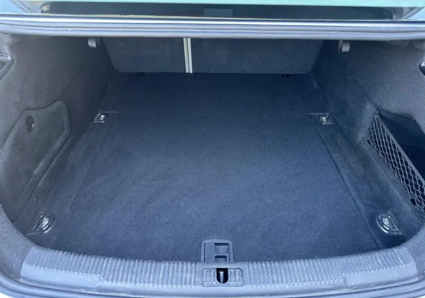 Coffre ouvert de l'Audi A6 gris, vue intérieure montrant un espace de rangement propre et vide avec filet latéral.