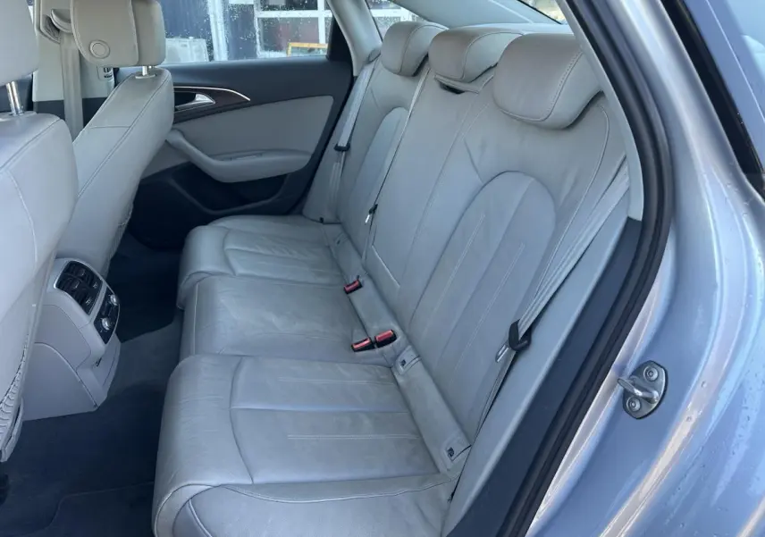 Vue intérieure côté droit montrant la banquette arrière en cuir gris clair de l'Audi A6 2015 avec accoudoirs et aérateurs centraux.