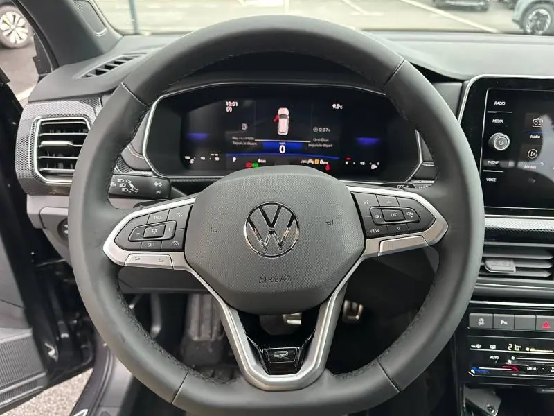 Vue rapprochée du volant cuir multifonction d’un Volkswagen T-Cross 2026 avec tableau de bord numérique et écran tactile.