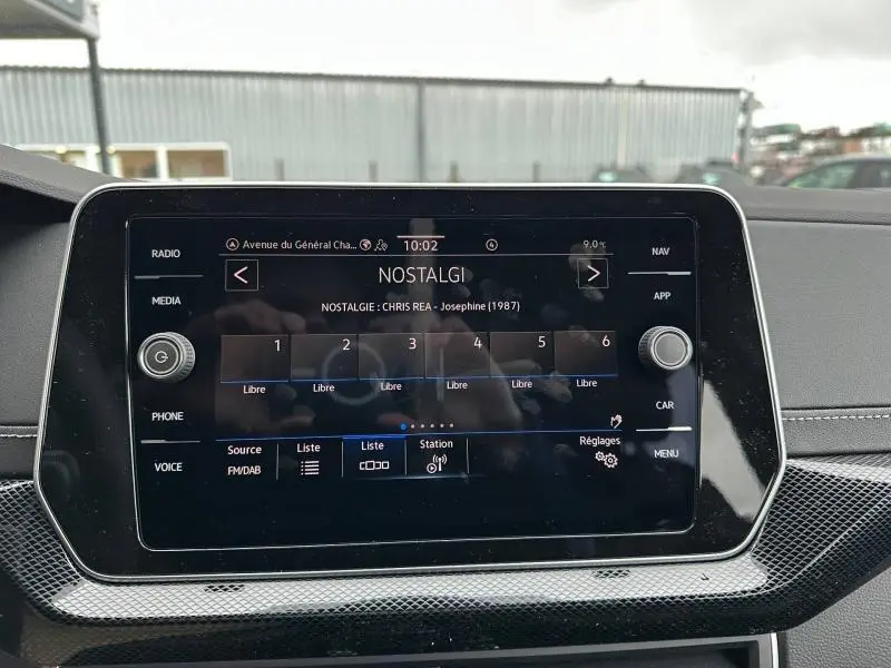 Écran tactile central du Volkswagen T-Cross 2026 affichant la radio sur fond noir avec commandes autour.