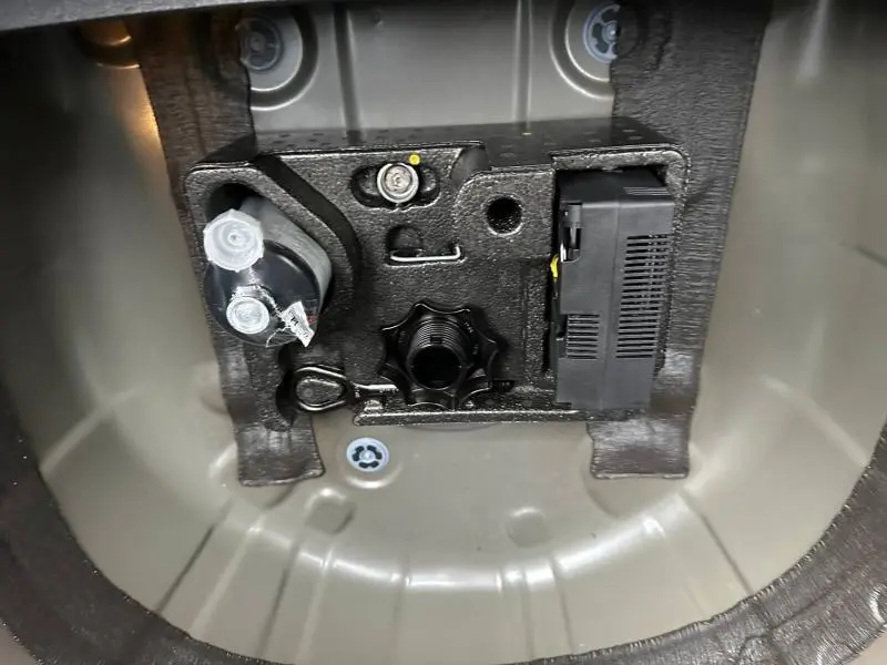 Gros plan sur le rangement sous le plancher du coffre du Volkswagen T-Cross jaune 2026, montrant les outils et accessoires.